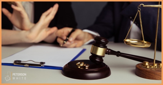 Woman with her hand up while a man is about to sign divorce papers